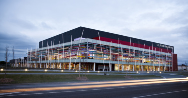 Events centre pictured at dusk with dramatic feature lighting and stylised light from passing road traffic