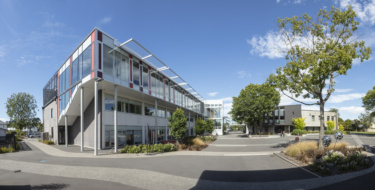 A panorama of the campus courtyard surrounded by glass fronted two story buildings.
